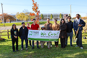 Tree Planting Ceremony 2025 - 1 Photo of President Moore standing with staff and students posing into front of a Tree Campus Banner