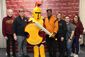 Lance Johnson posing with Troy the Mascot and Alumni Members