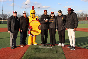 Troy the Mascot, President Moore and Lance Johnson with Alumni members on Pitcher's mound