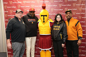 Troy the Mascot posing with Prsident Moore and Alumni Members