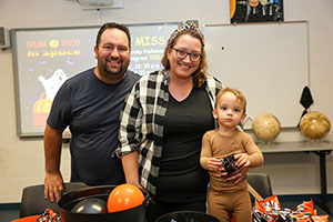 Couple with child handing out candy at Trunk or Treat 