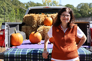 Photo of President Moore standing in front of a pick up truck loaded with pumpkins
