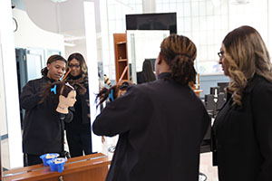 Photo of Instructor and student styling hair with a mannequin head while looking at a mirror