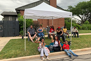 Photo of parade viewers sitting under tent